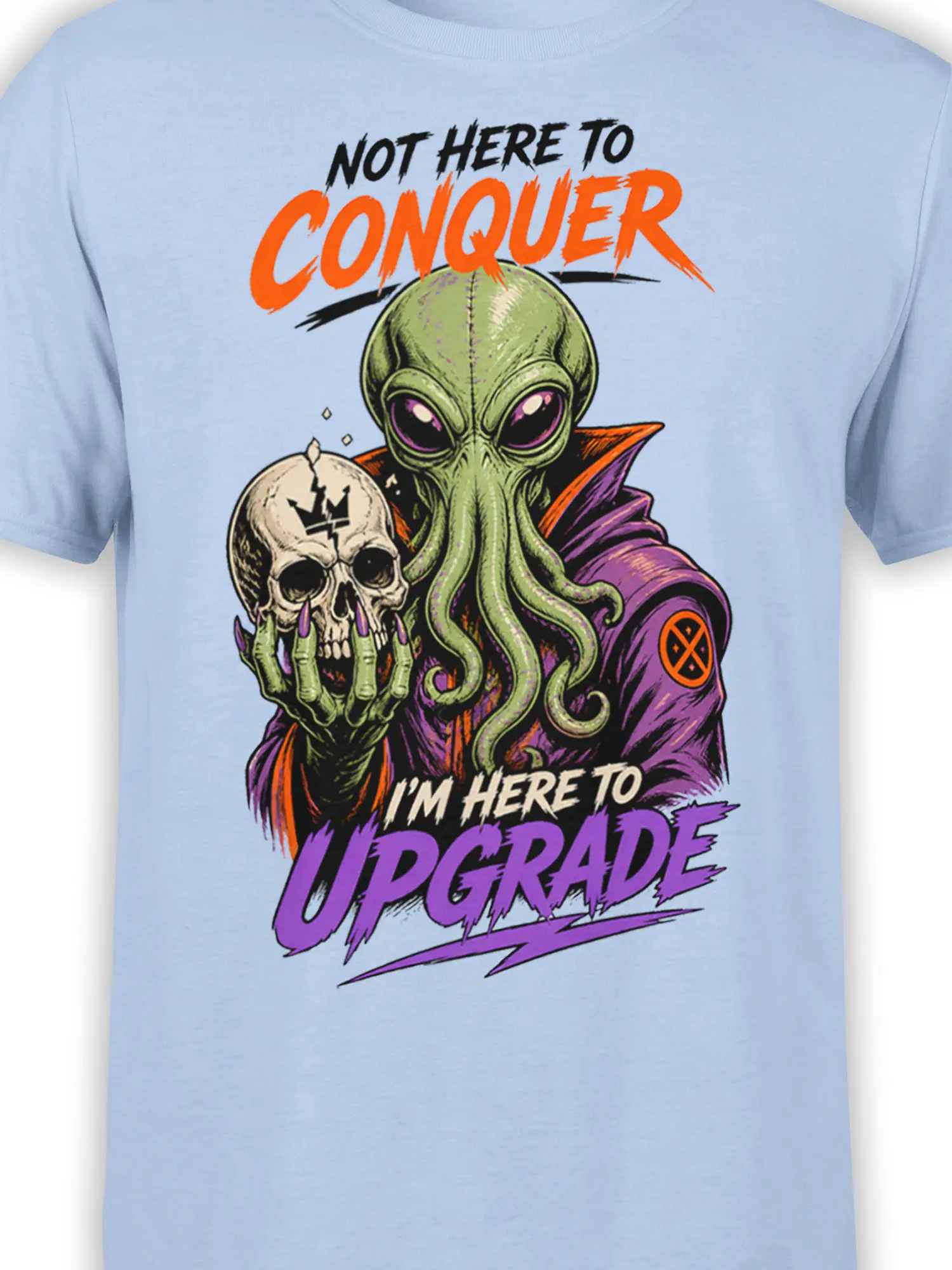 Close-up of green alien, skull, and colorful upgrade artwork on a light blue graphic tee