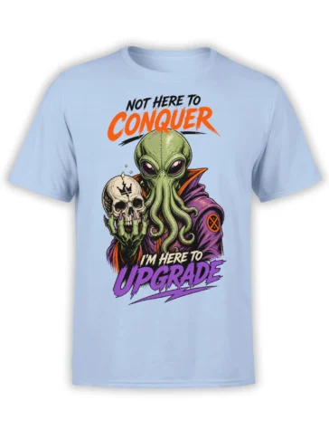 Green alien holding a cracked skull on a light blue shirt with bold “Not Here to Conquer” lettering