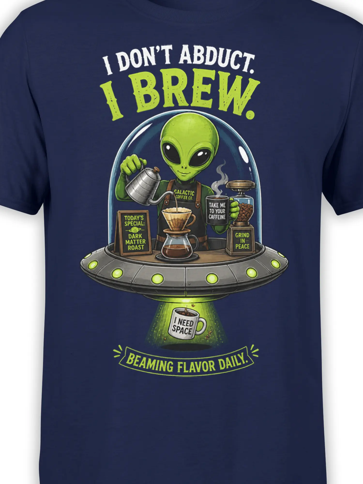 Close-up of green alien barista, coffee brewer, and UFO artwork on a navy T-shirt