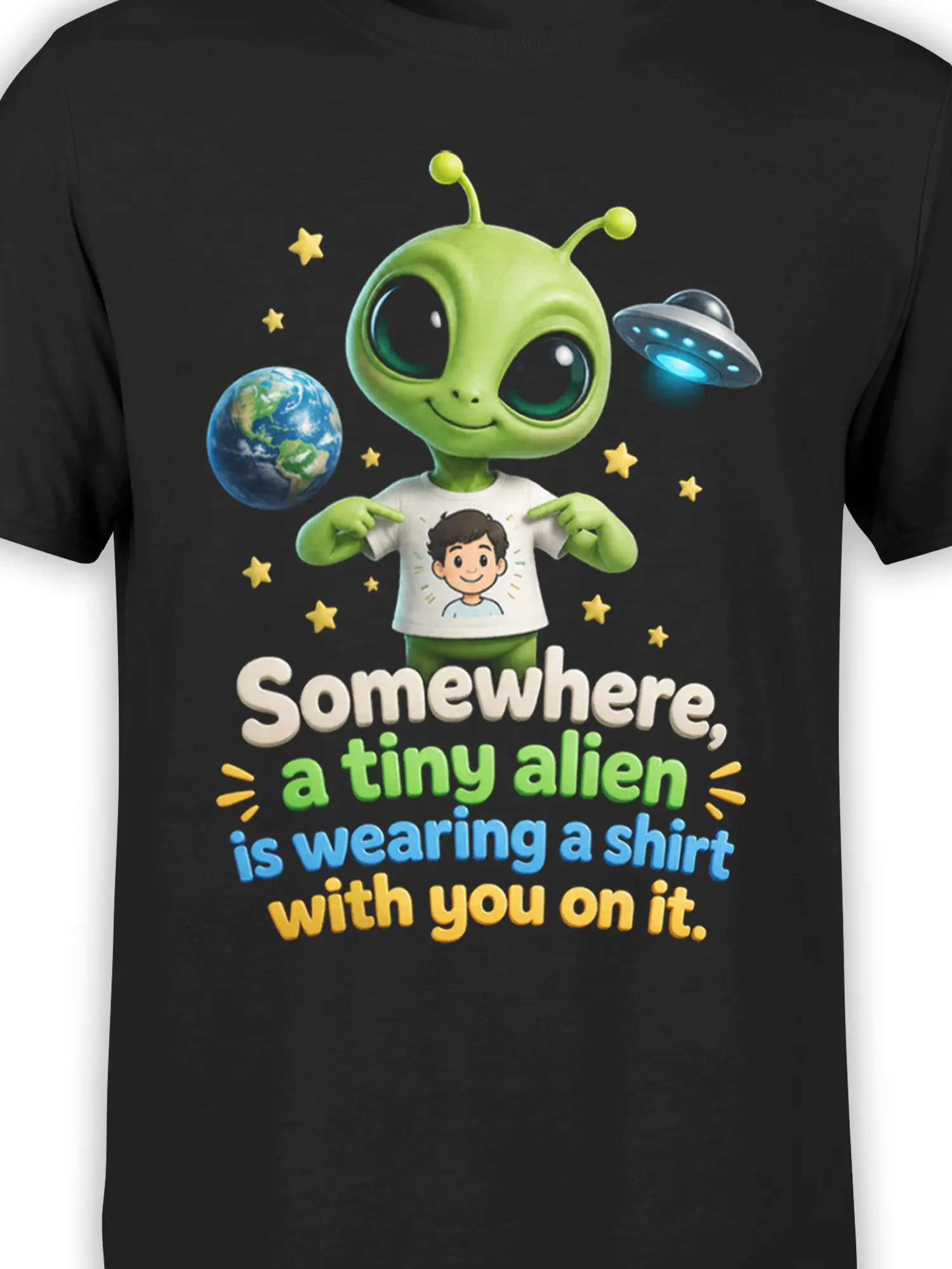 Close-up of green alien graphic, Earth, UFO, stars, and colorful slogan on a black T-shirt