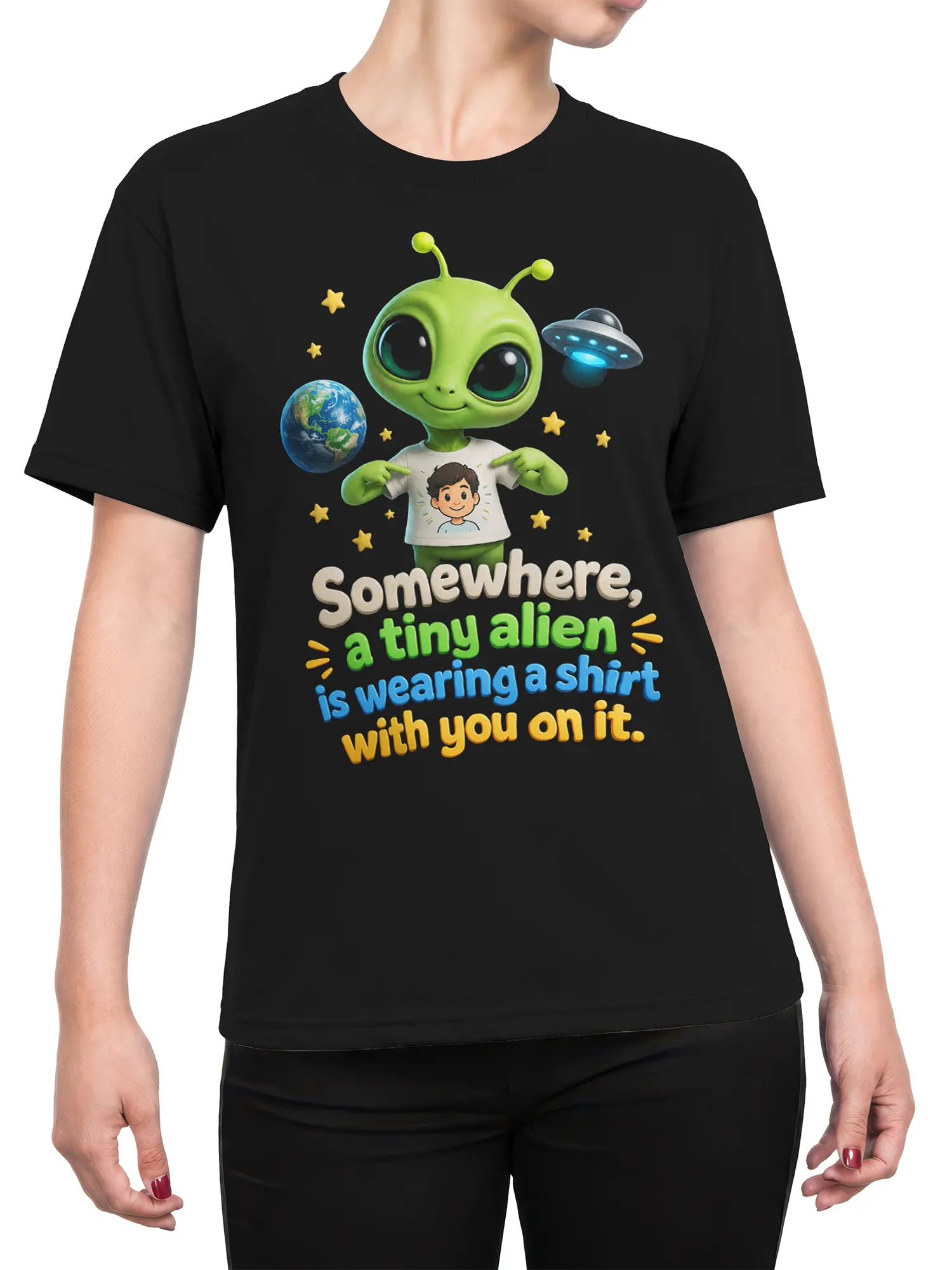 Female torso wearing a black T-shirt with a cute green alien, Earth, UFO, stars, and colorful slogan