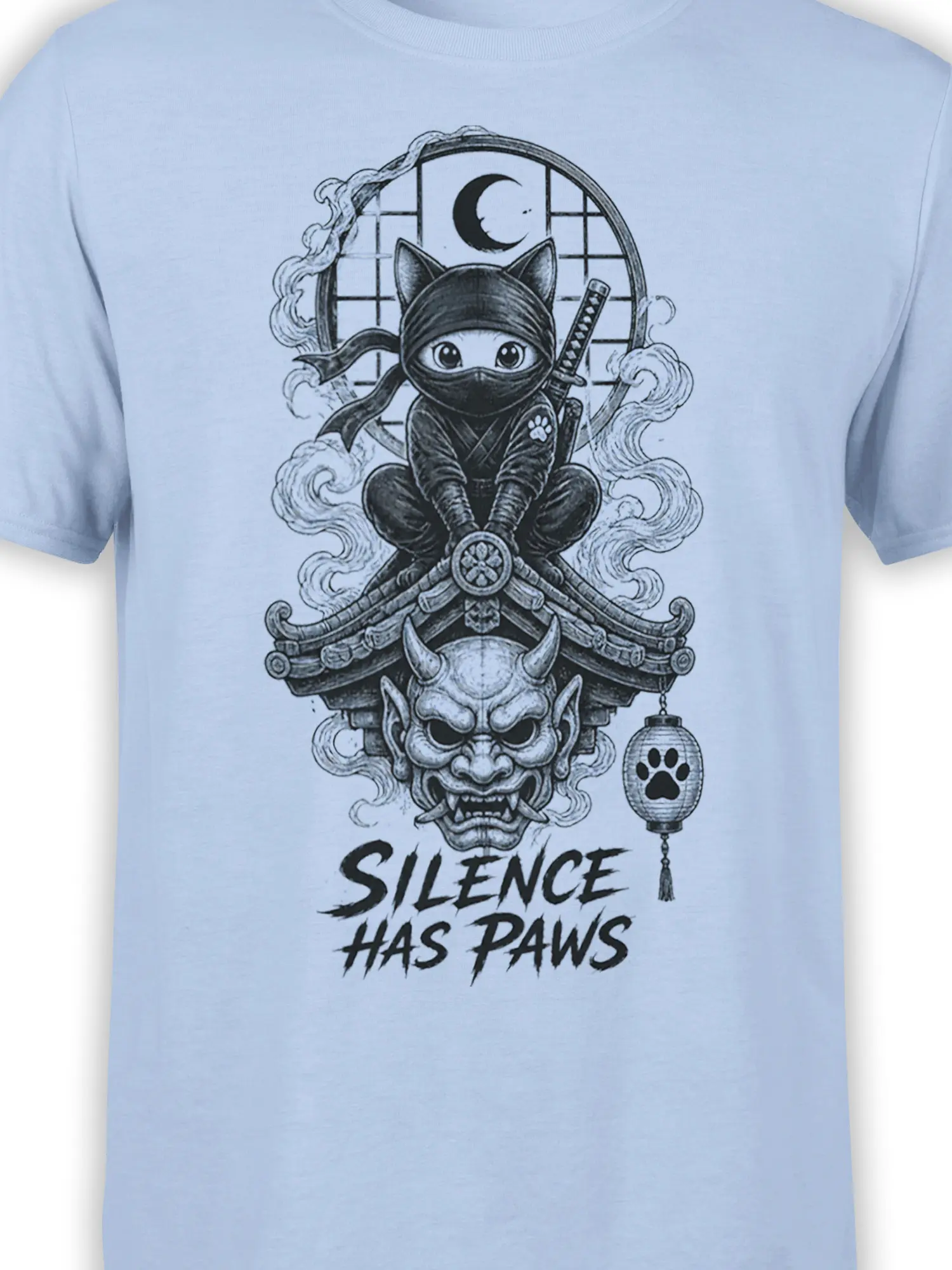 Close-up of the ninja cat graphic on a light blue shirt with moon, roof, demon face, lantern, and paw details