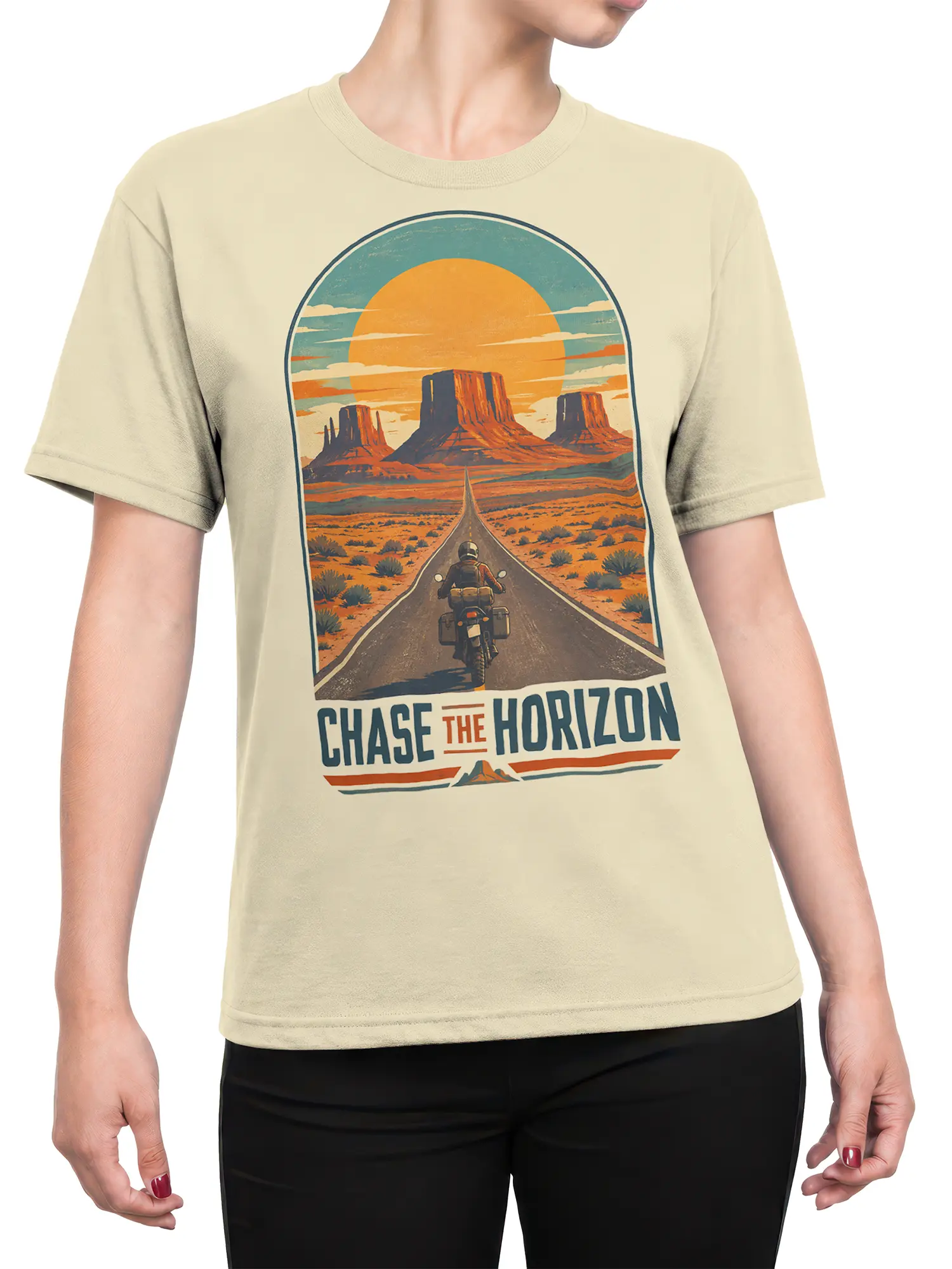 Female torso wearing a beige T-shirt with a retro desert highway, motorcyclist, mesas, orange sun, and horizon message