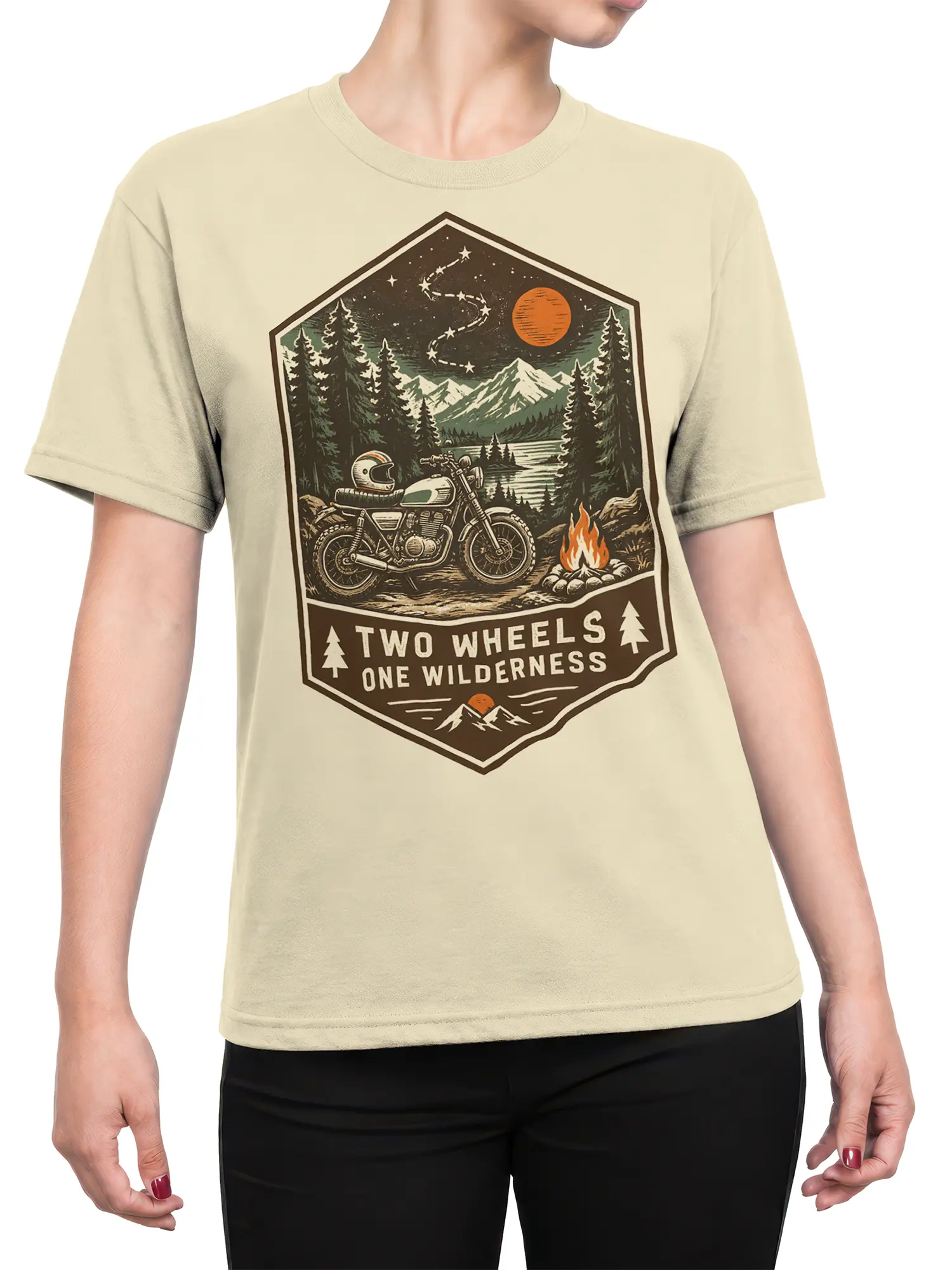 Female torso wearing a beige motorcycle T-shirt with a vintage mountain, lake, campfire, and pine forest graphic