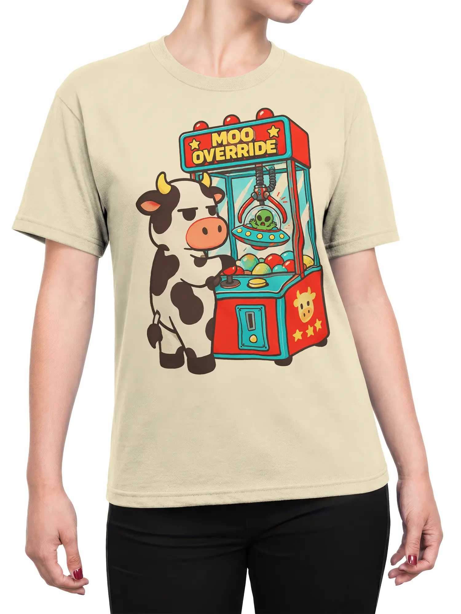 Female torso wearing a beige T-shirt with a cow and alien claw machine graphic