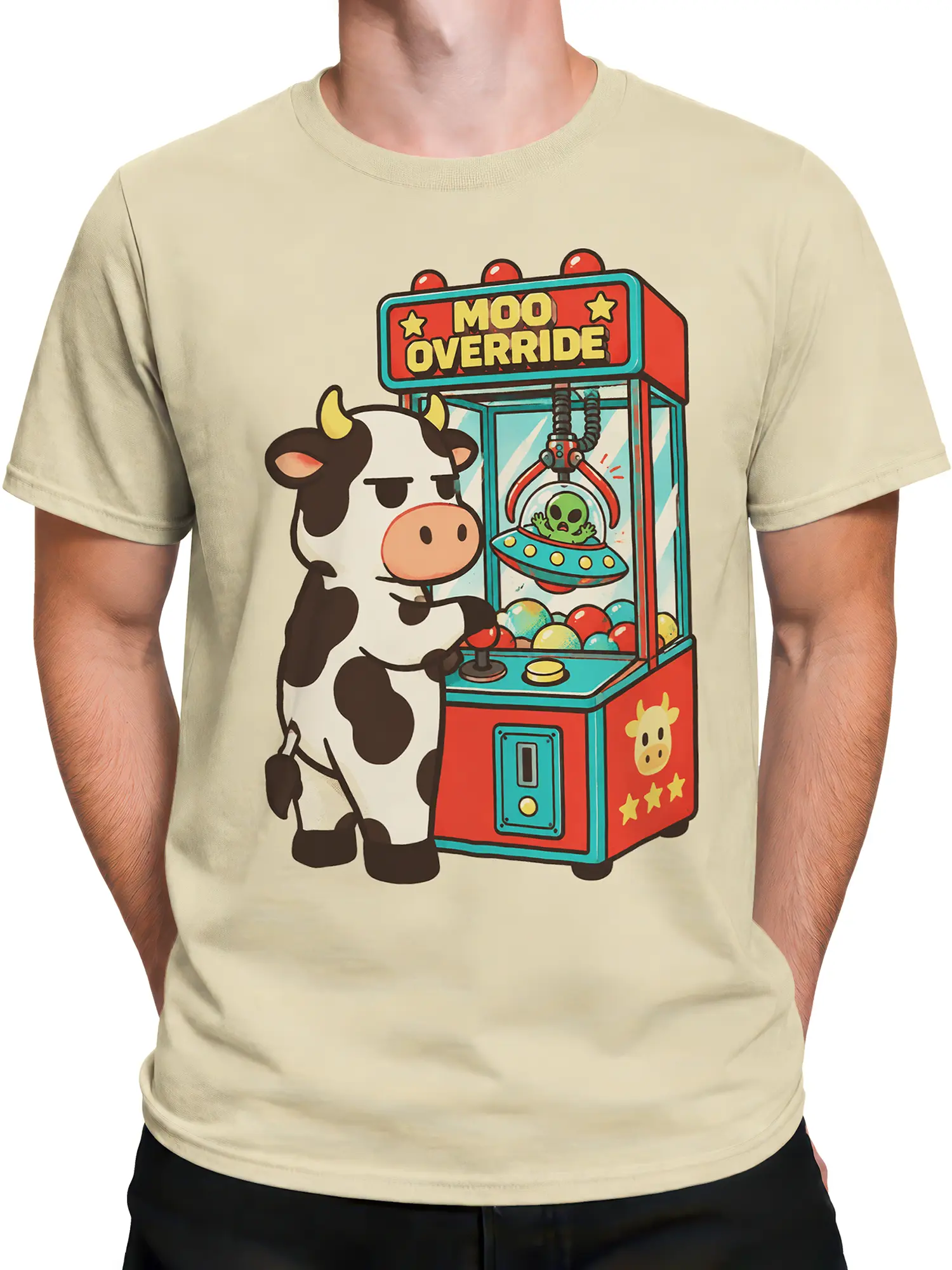 Male torso wearing a beige cow graphic T-shirt with an alien claw machine design