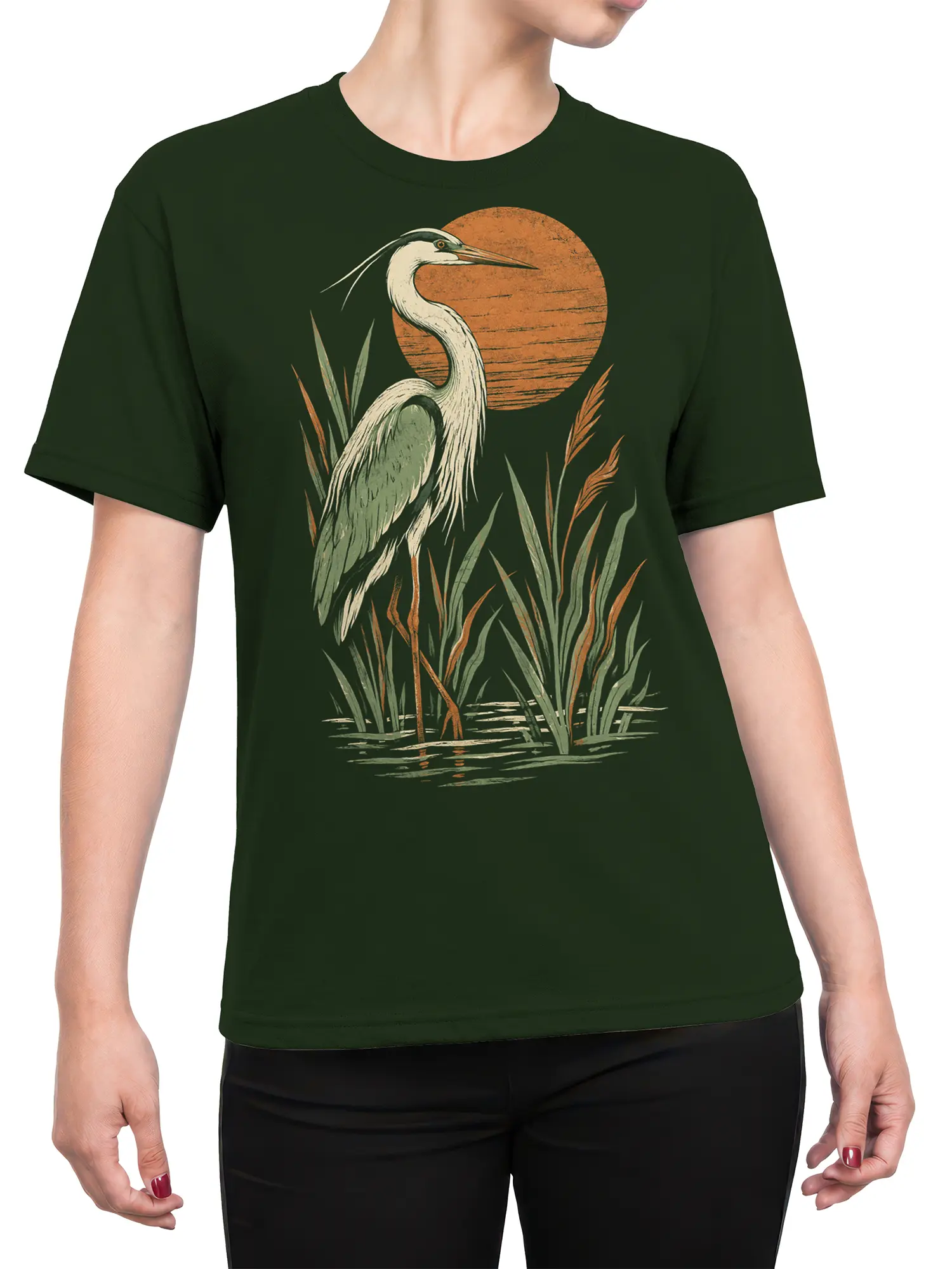 Female torso wearing a dark green heron graphic t-shirt with marsh reeds and a warm orange sky design