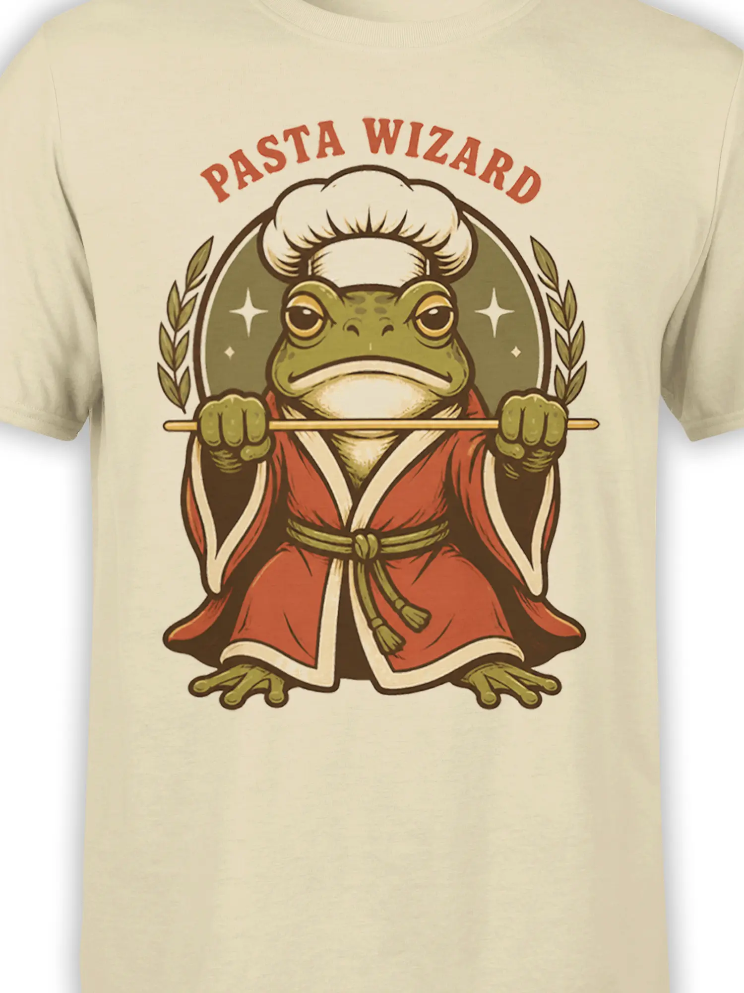 Close-up of the green frog chef wizard design and Pasta Wizard lettering on a beige T-shirt