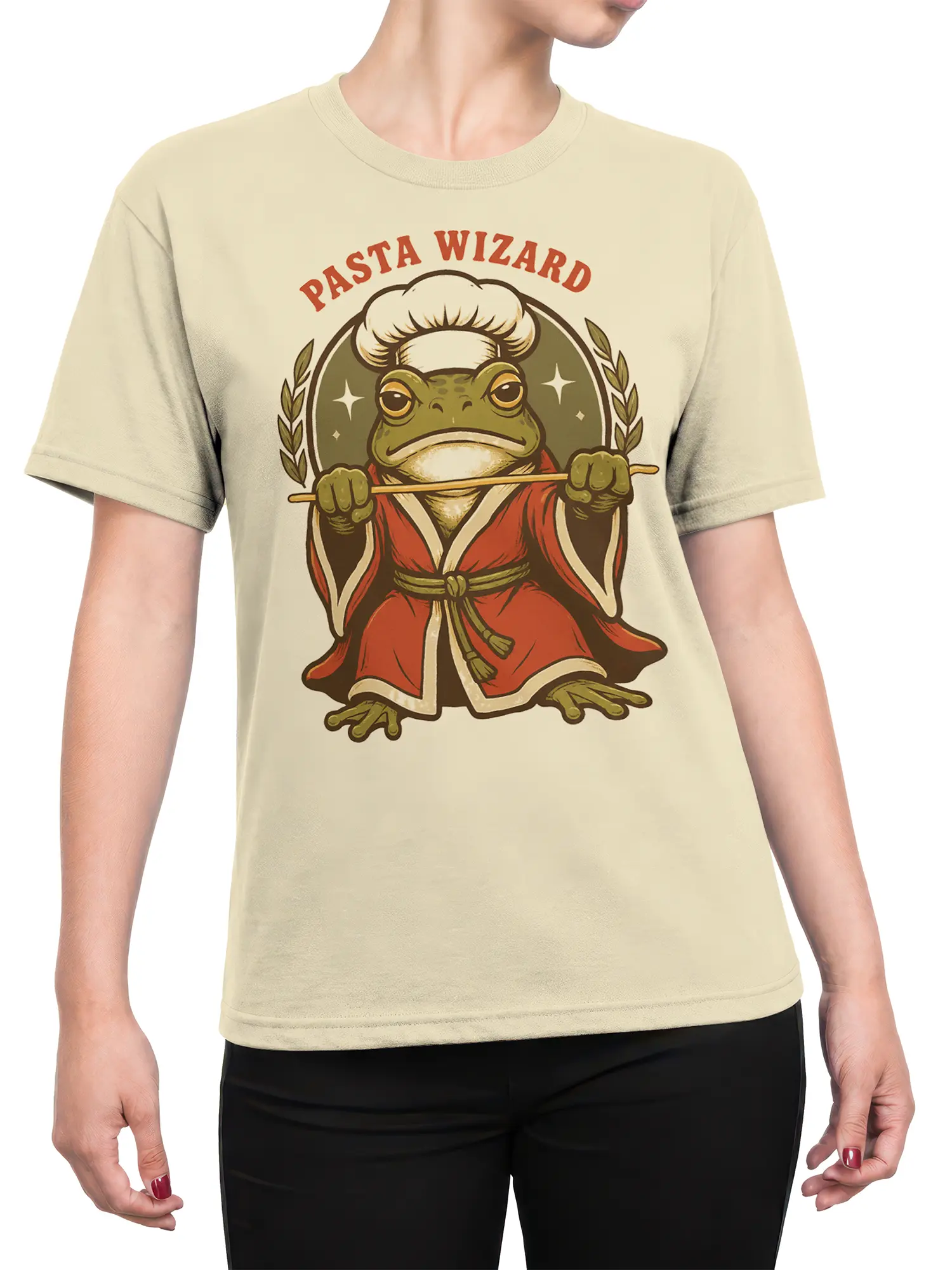 Female torso wearing a beige Pasta Wizard T-shirt with a green frog chef wizard graphic