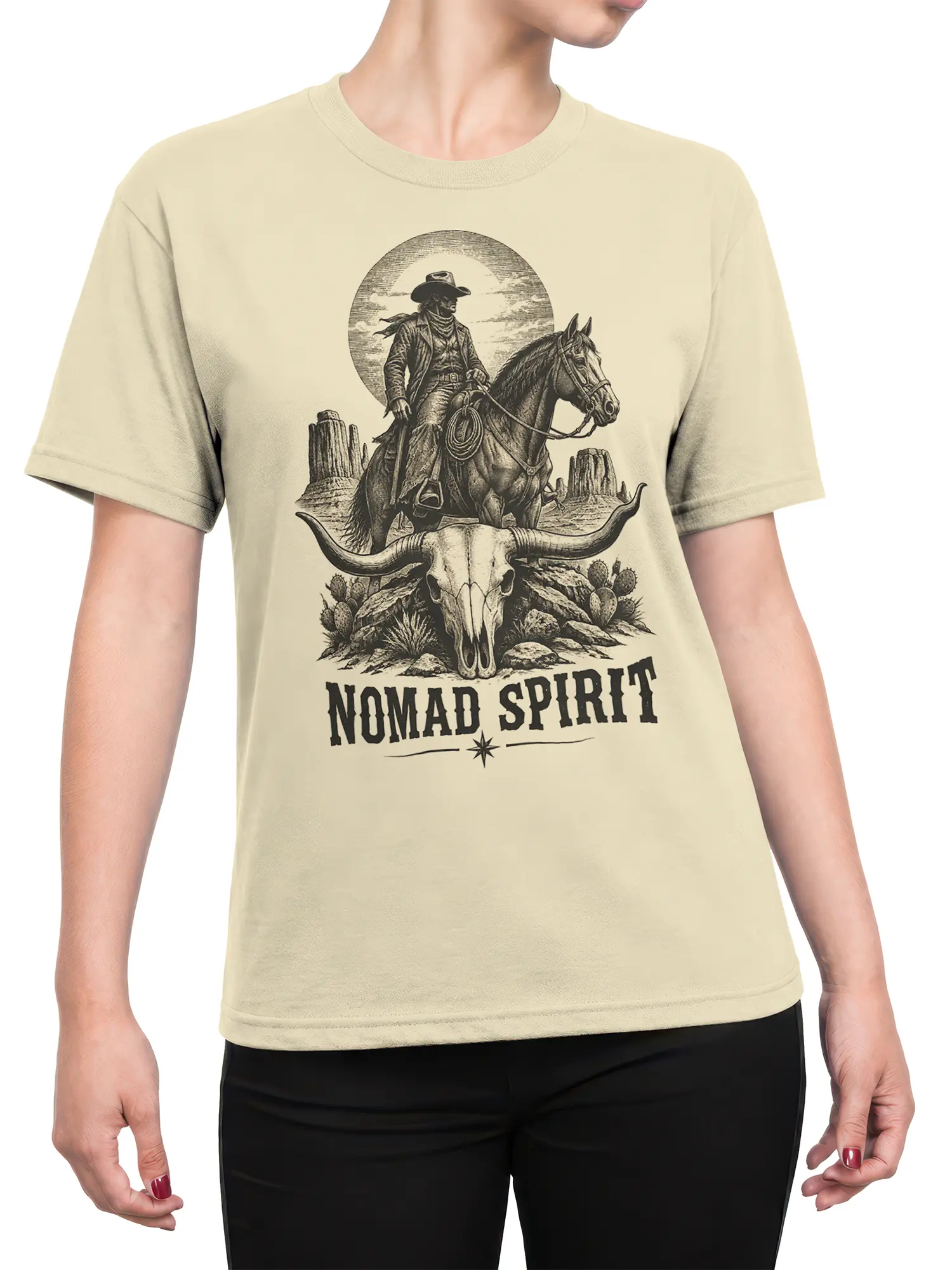 Female torso wearing beige western t-shirt with cowboy, horse, desert, and Nomad Spirit graphic